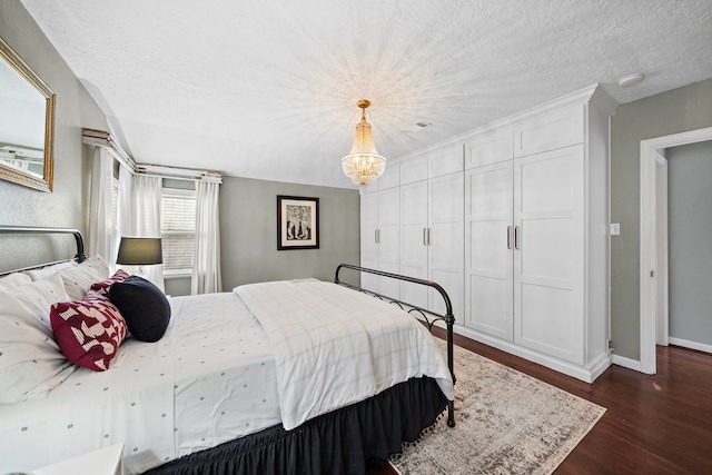 bedroom with a textured ceiling, a notable chandelier, baseboards, and dark wood-type flooring