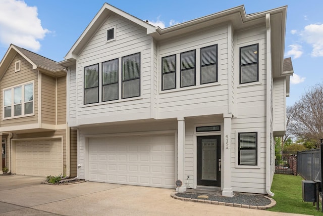 view of property featuring a garage, fence, central air condition unit, and concrete driveway