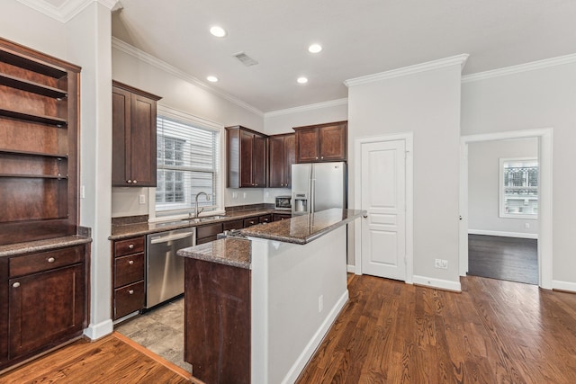 kitchen with dark brown cabinetry, a kitchen island, visible vents, appliances with stainless steel finishes, and a sink