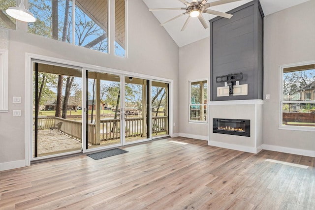 unfurnished living room with baseboards, high vaulted ceiling, and wood finished floors
