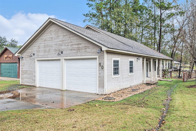 view of side of property featuring a detached garage, a yard, and roof with shingles