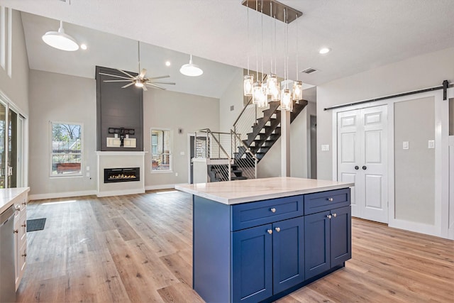 kitchen with light wood-style floors, hanging light fixtures, a ceiling fan, and blue cabinetry