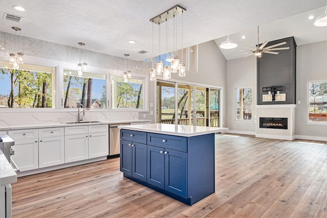 kitchen with light wood-type flooring, a sink, white cabinetry, and a textured ceiling