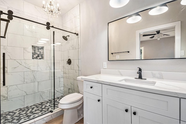 bathroom featuring vanity, ceiling fan with notable chandelier, a stall shower, and toilet