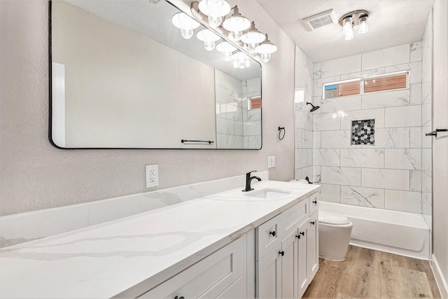 bathroom featuring vanity, toilet, shower / bath combination, wood finished floors, and visible vents