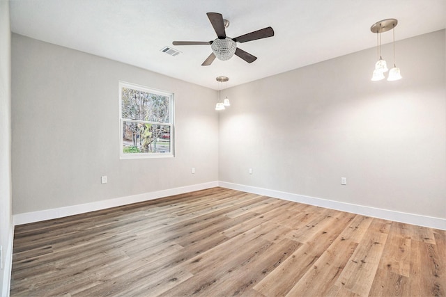 unfurnished room featuring baseboards, ceiling fan with notable chandelier, wood finished floors, and visible vents