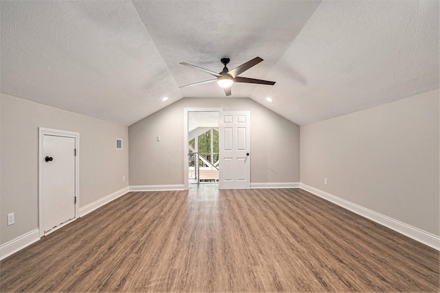 additional living space with baseboards, ceiling fan, dark wood-style floors, a textured ceiling, and vaulted ceiling