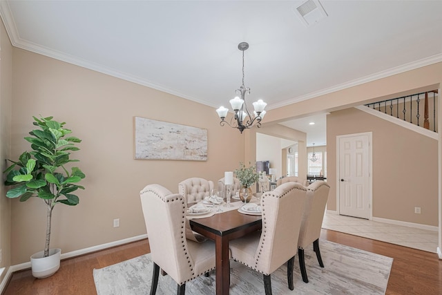 dining space featuring visible vents, crown molding, baseboards, a notable chandelier, and light wood-style floors