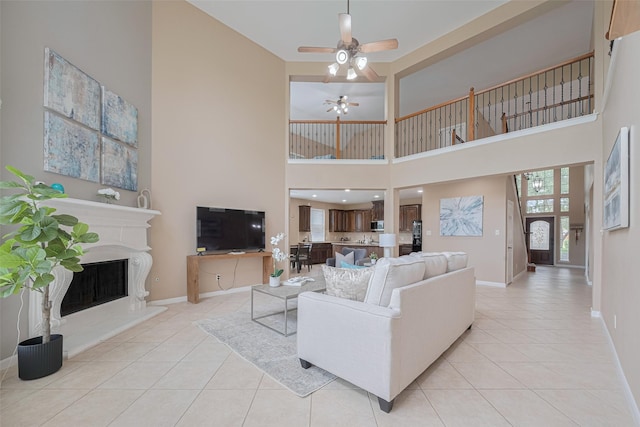 living area with light tile patterned floors, baseboards, a high ceiling, and a ceiling fan