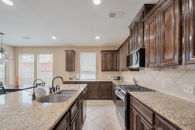 kitchen featuring visible vents, dark brown cabinets, light stone counters, a sink, and appliances with stainless steel finishes