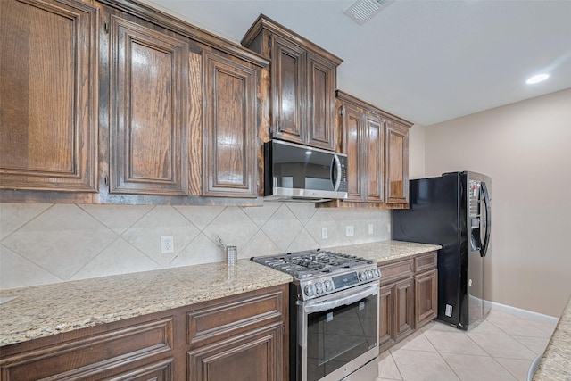 kitchen featuring visible vents, tasteful backsplash, baseboards, light stone counters, and stainless steel appliances