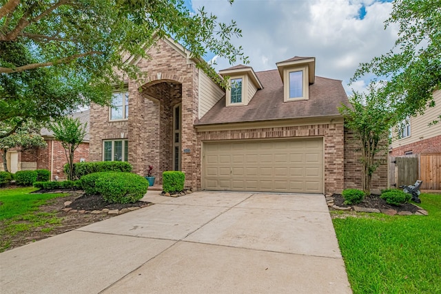 traditional-style home featuring roof with shingles, a garage, brick siding, fence, and concrete driveway