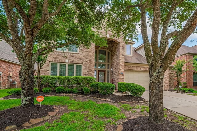 traditional home featuring an attached garage, concrete driveway, and brick siding
