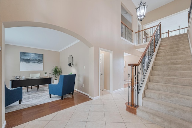 tiled entrance foyer featuring stairway, arched walkways, ornamental molding, and baseboards