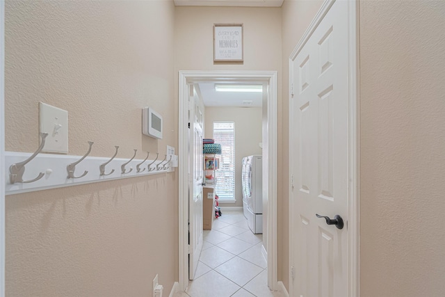 hallway with washer / dryer and light tile patterned flooring