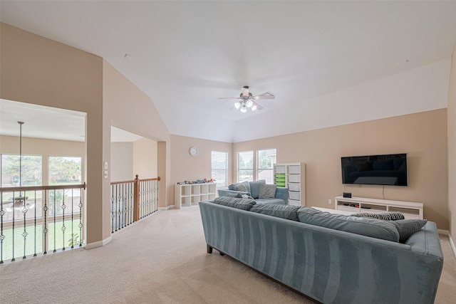 living area with baseboards, ceiling fan, light carpet, and lofted ceiling