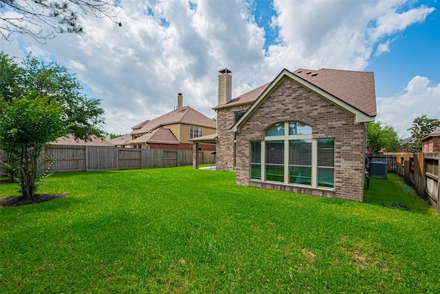 rear view of house featuring a fenced backyard, a chimney, brick siding, a shingled roof, and a yard