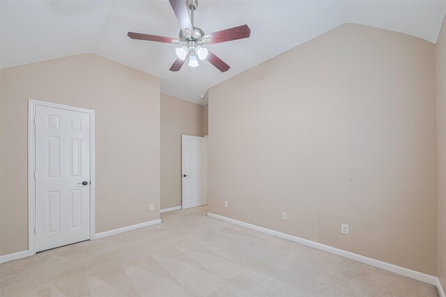 unfurnished bedroom featuring light colored carpet, baseboards, vaulted ceiling, and a ceiling fan