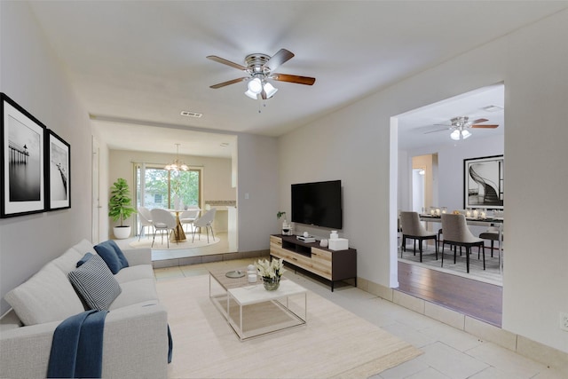 living area featuring visible vents, ceiling fan with notable chandelier, and tile patterned flooring