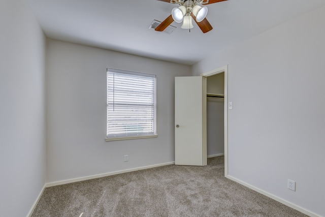 unfurnished bedroom with carpet floors, visible vents, baseboards, ceiling fan, and a spacious closet