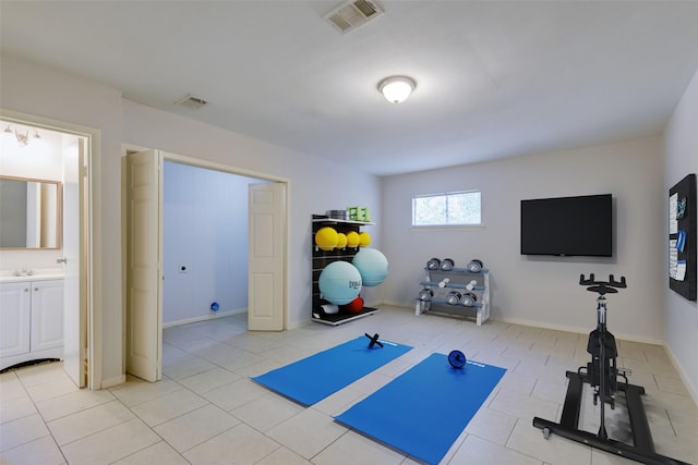 exercise area featuring light tile patterned flooring, visible vents, and a sink