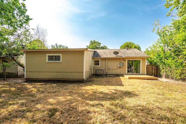 rear view of house featuring fence and a yard