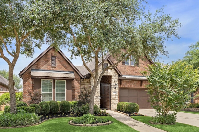 27018 Camirillo Creek Ln, Katy, TX 77494 - english style home with brick siding, a garage, stone siding, a front yard, and concrete driveway