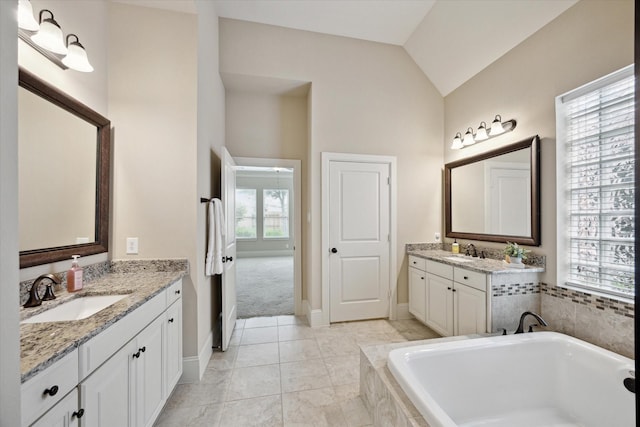 27018 Camirillo Creek Ln, Katy, TX 77494 - bathroom with a relaxing tiled tub, vaulted ceiling, two vanities, and a sink