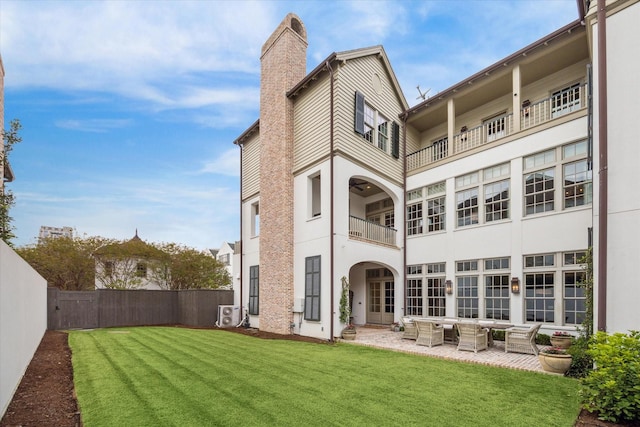 56 Audubon Hollow Ln, Houston, TX 77027 - back of house with fence, a balcony, stucco siding, a chimney, and a lawn