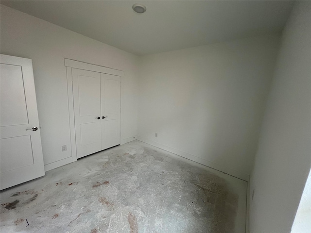 unfurnished bedroom featuring concrete flooring and a closet