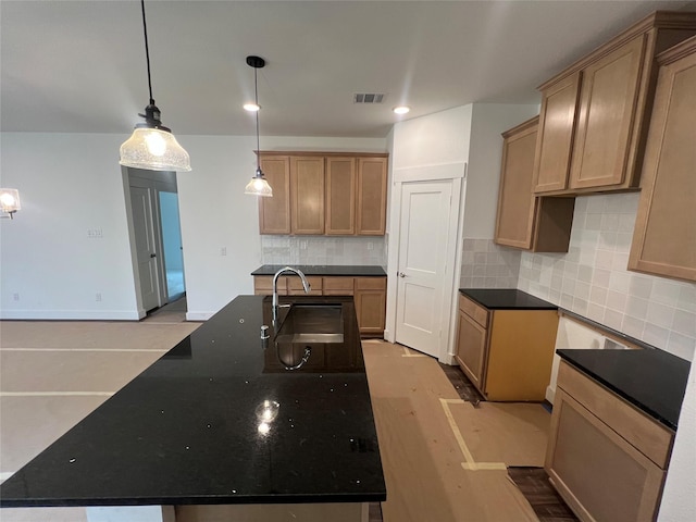 kitchen with visible vents, decorative backsplash, pendant lighting, a kitchen island with sink, and a sink