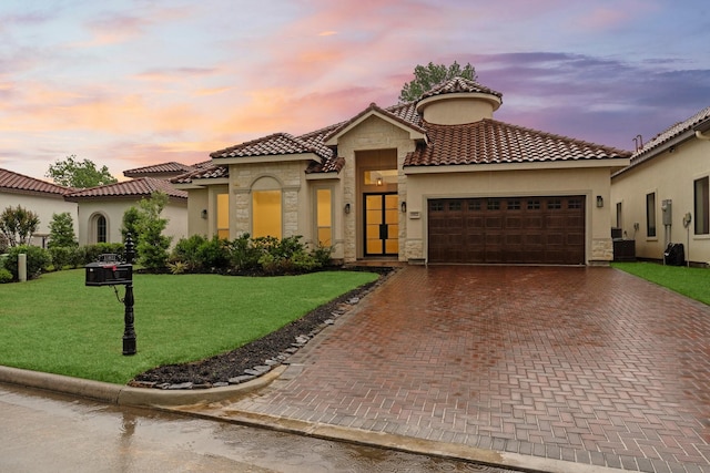 mediterranean / spanish home featuring an attached garage, a front yard, decorative driveway, and stone siding