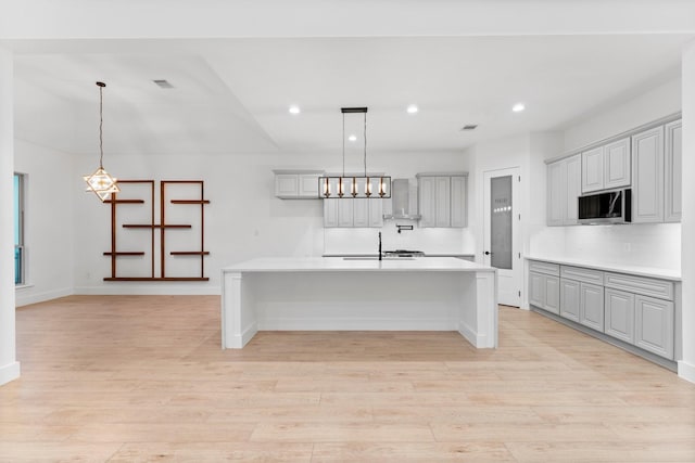 kitchen with light wood-style floors, light countertops, a sink, and stainless steel microwave