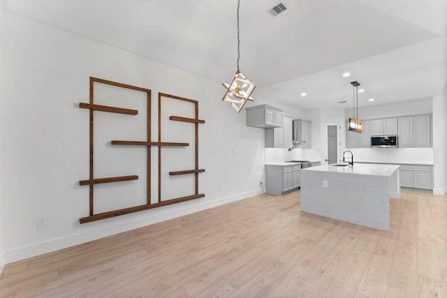 kitchen with visible vents, gray cabinetry, light countertops, a sink, and stainless steel appliances