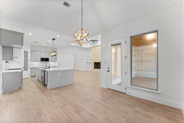 kitchen with visible vents, an inviting chandelier, light countertops, stainless steel microwave, and a sink