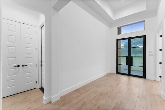 entrance foyer featuring a raised ceiling, baseboards, and light wood finished floors