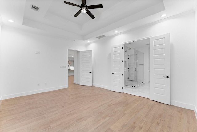 unfurnished bedroom with recessed lighting, a tray ceiling, visible vents, and light wood-type flooring