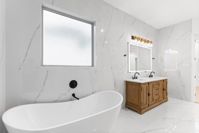 bathroom with double vanity, a sink, marble finish floor, and a freestanding tub
