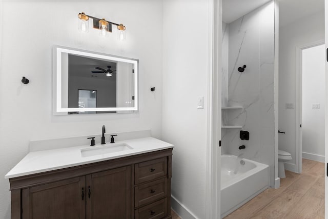 full bath featuring ceiling fan, vanity, shower / bathtub combination, toilet, and wood finished floors