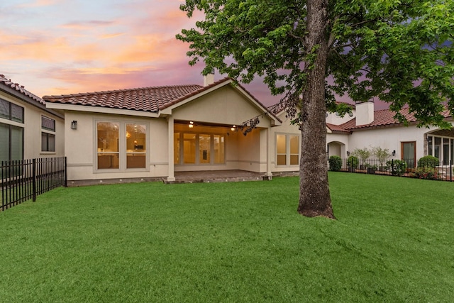 back of house with a lawn, fence, a tile roof, and stucco siding