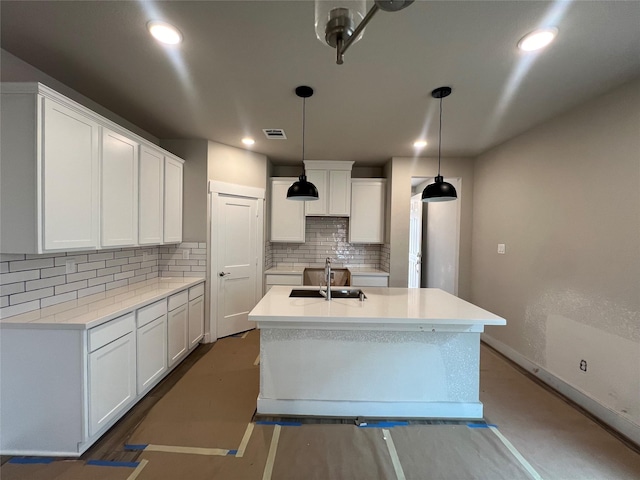 kitchen with visible vents, decorative backsplash, an island with sink, white cabinets, and a sink