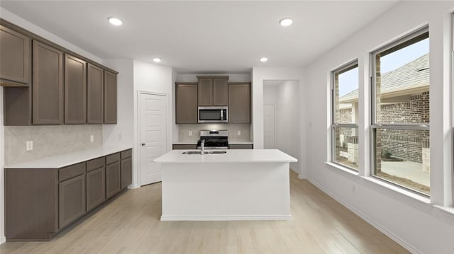kitchen featuring light countertops, tasteful backsplash, a kitchen island with sink, and stainless steel appliances