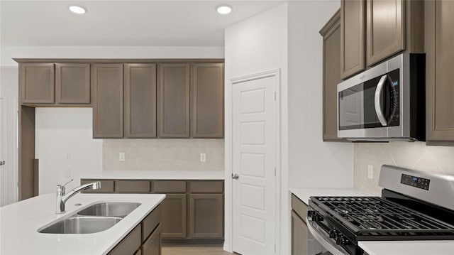 kitchen with a sink, appliances with stainless steel finishes, tasteful backsplash, and light countertops
