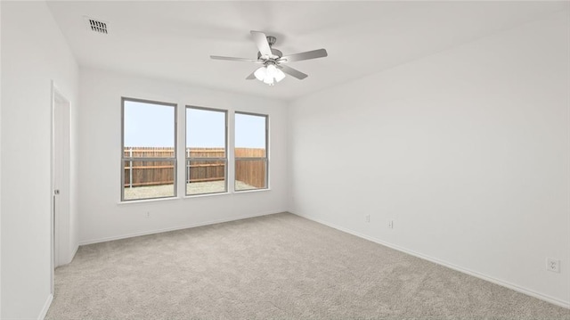 empty room with light colored carpet, baseboards, ceiling fan, and visible vents