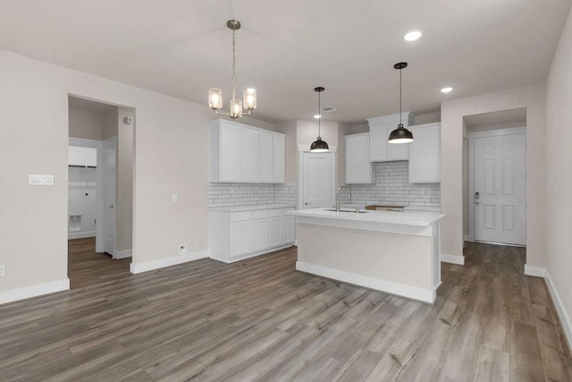 4807 Sand Clouds Dr, Katy, TX 77493 - kitchen with decorative backsplash, wood finished floors, baseboards, an island with sink, and white cabinets