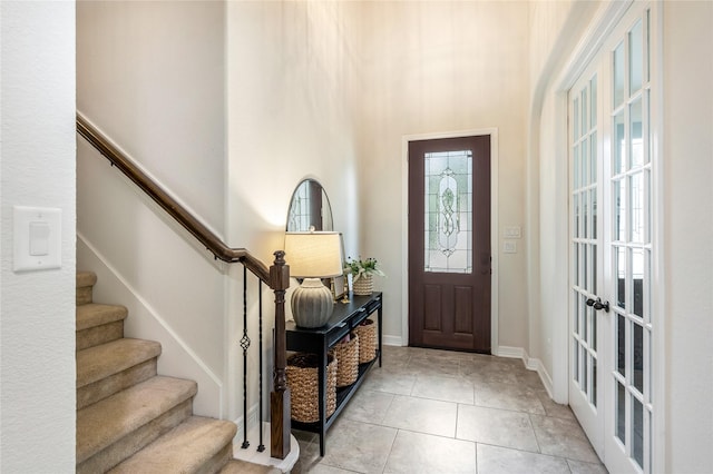 foyer featuring stairs, a high ceiling, and light tile patterned floors