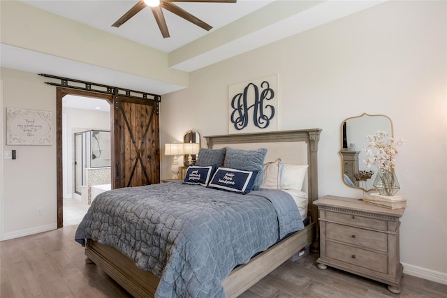 bedroom with baseboards, a barn door, ceiling fan, and wood finished floors