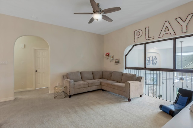 carpeted living room with baseboards, a ceiling fan, and arched walkways