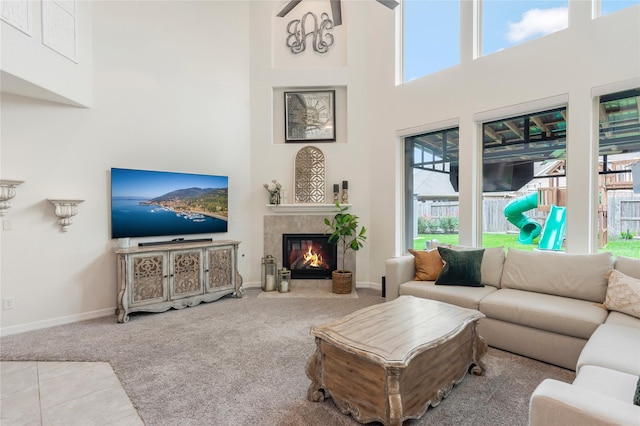 carpeted living room featuring a fireplace with flush hearth, baseboards, and a high ceiling