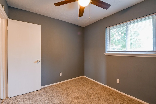 carpeted spare room with ceiling fan and baseboards